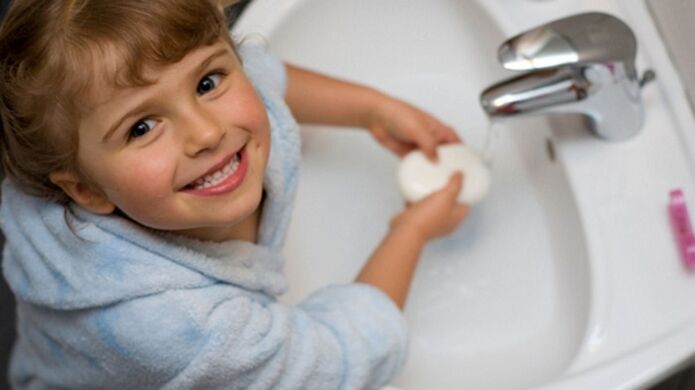 Il bambino si lava le mani con sapone per prevenire i vermi